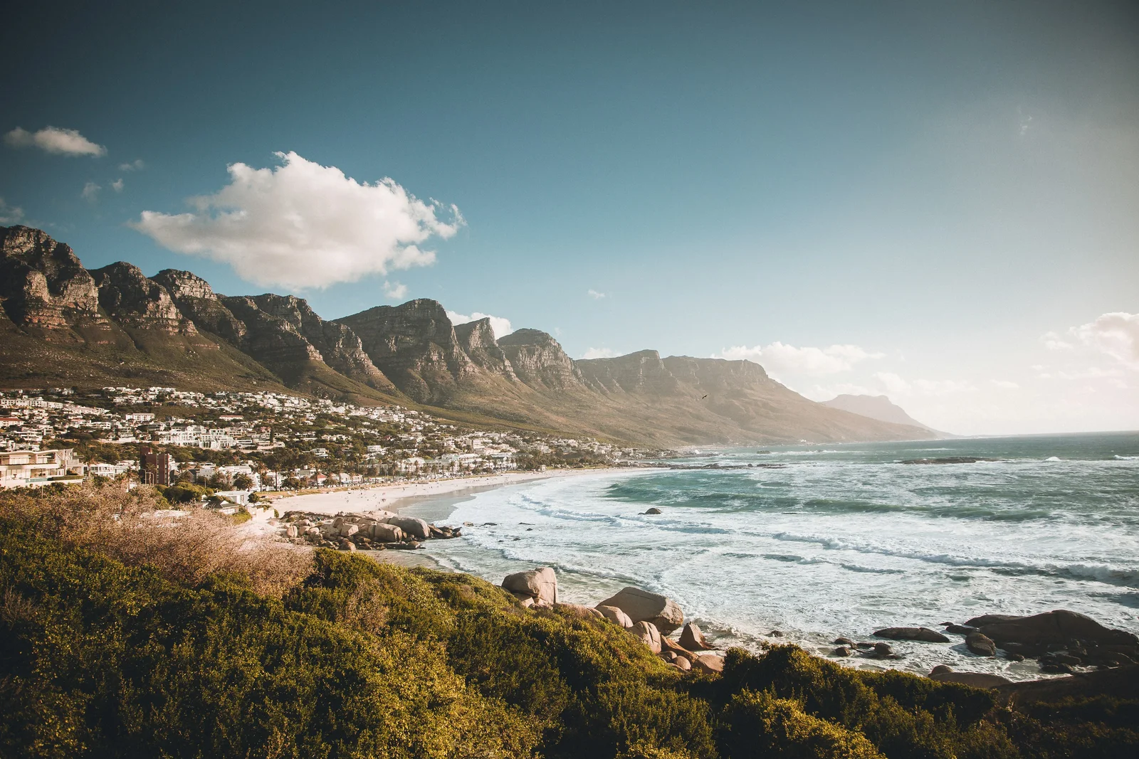 Waves rolling into Camps Bay beneath South Africa's Twelve Apostles mountains.
